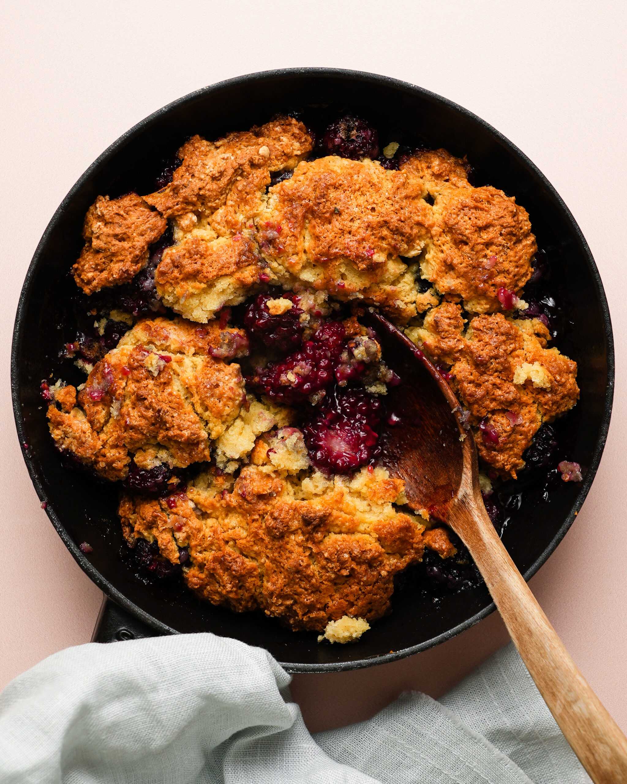A fresh blackberry cobbler sits at the center of the image.