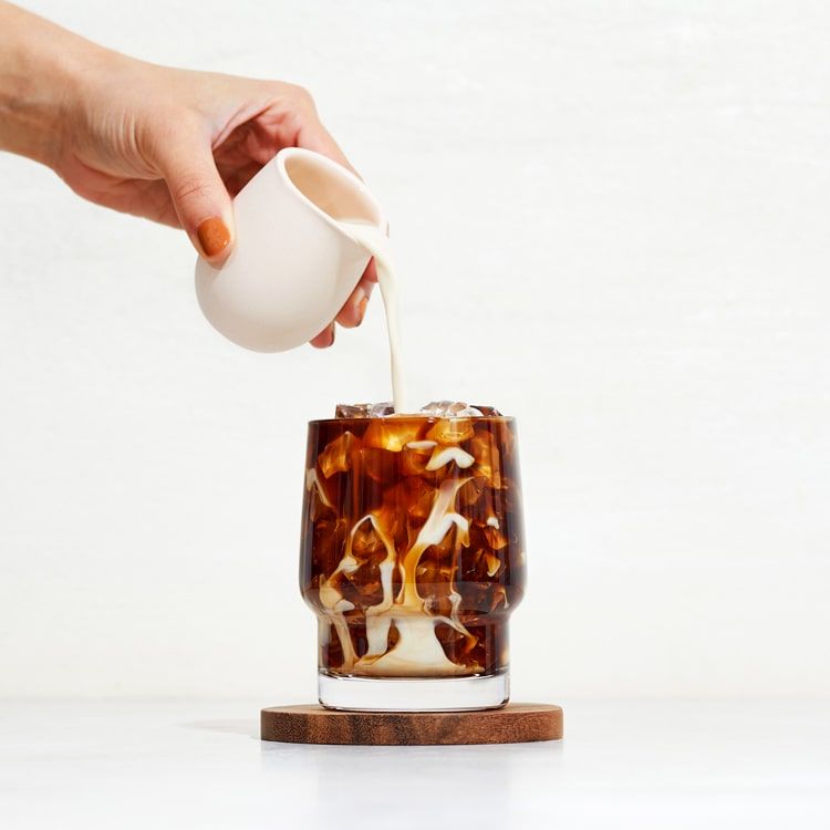 oat milk being poured in iced coffee